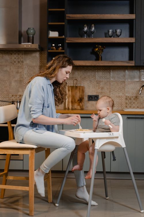 Nouvelle maman avec son bébé dans la cuisine de sa maison